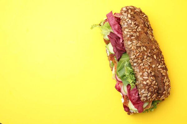 Delicious sandwich with schnitzel on yellow background, top view. Space for text