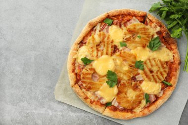 Gri masa üzerinde lezzetli ananaslı pizza ve maydanoz. Metin için boşluk