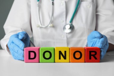 Doktor beyaz masadaki harflerle ahşap küplerden kelime donörü yapıyor.