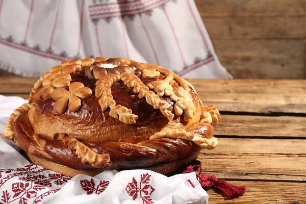 Korovai with rushnyk on wooden table. Ukrainian bread and salt welcoming tradition