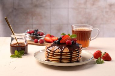 Lezzetli krepler, taze böğürtlen, çikolata sosu ve beyaz masada nane şekeri.