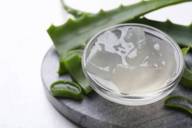 Aloe vera jeli ve bitki dilimleri beyaz arka planda, yakın plan. Metin için boşluk