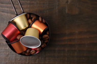 Kahve kapsüllü tencere ve ahşap masa üzerinde fasulye, üst manzara. Metin için boşluk