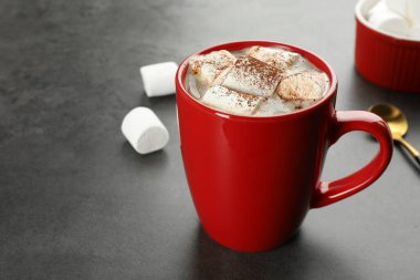 Gri masadaki kremalı ve kakao tozlu lezzetli sıcak çikolata, yakın plan. Metin için boşluk