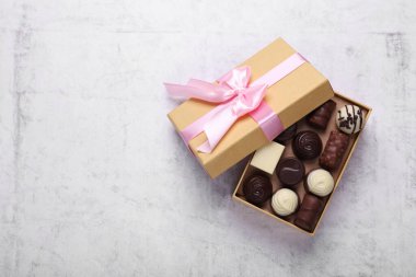 Beyaz masa üzerinde nefis çikolata şekerleri olan açık bir kutu, üst manzara. Metin için boşluk