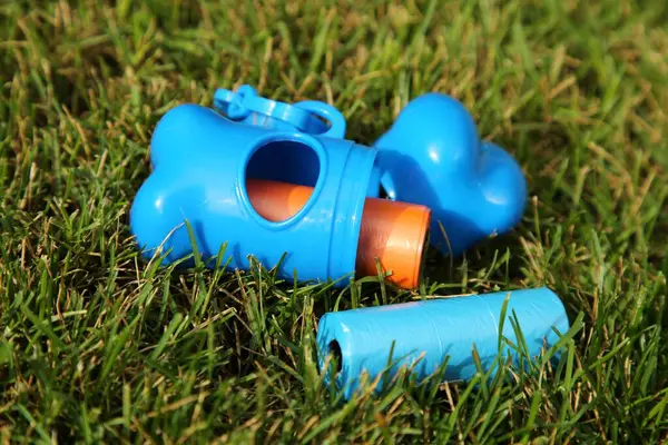 stock image Rolls of colorful dog waste bags on green grass outdoors