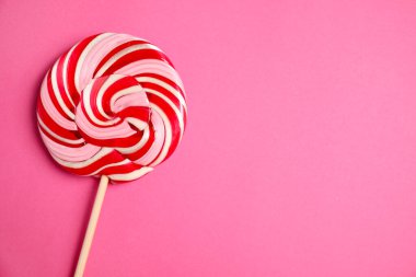 Pembe arka planda renkli lolipop kıvrımlı, üst manzaralı. Metin için boşluk