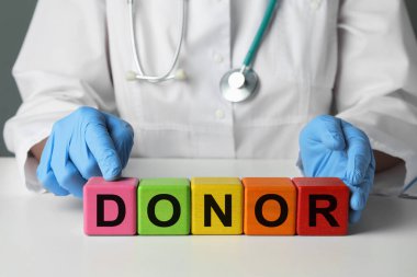 Doktor beyaz masadaki harflerle ahşap küplerden kelime donörü yapıyor.