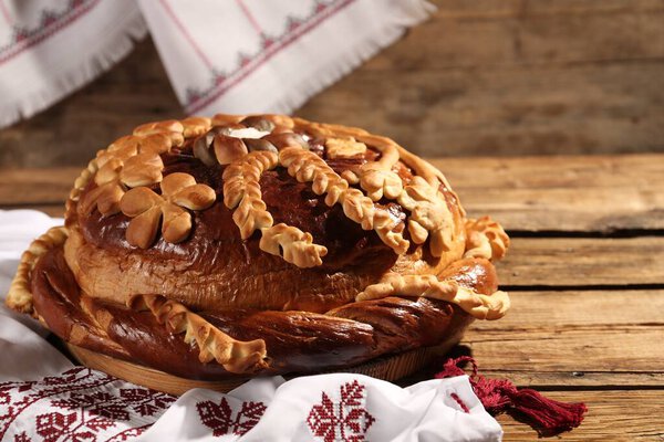 Korovai with rushnyk on wooden table. Ukrainian bread and salt welcoming tradition