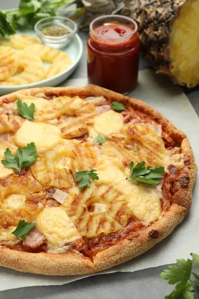 Delicious pineapple pizza with parsley on table