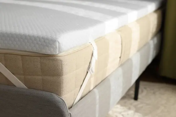 White memory foam mattress topper on grey bed, closeup