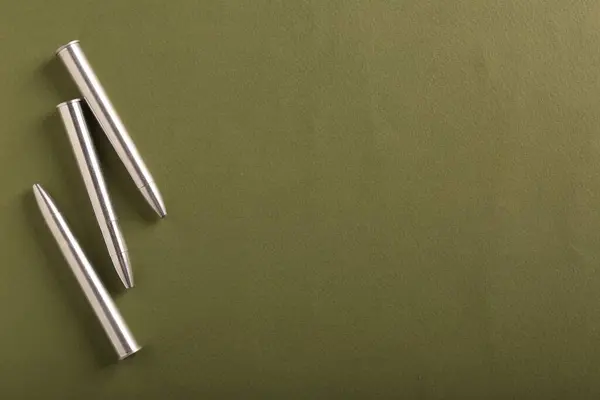 Many metal bullets on green background, flat lay. Space for text