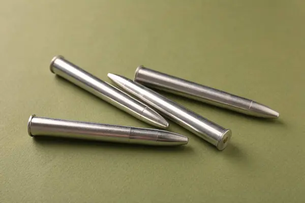 Many metal bullets on green background, closeup