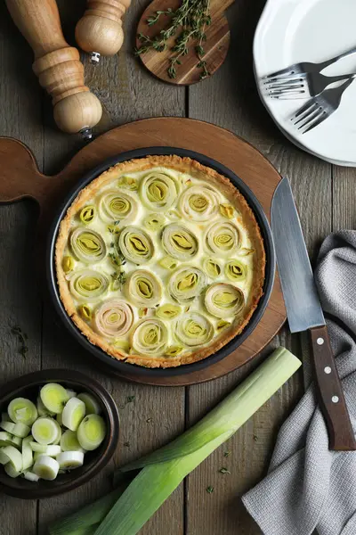 Lezzetli pırasalı turta ve ahşap masa malzemeleriyle düz kompozisyon.