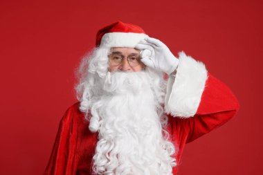 Mutlu noeller. Noel Baba kırmızı arka planda poz veriyor