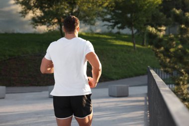 Güneşli bir günde, arka planda koşan bir adam.