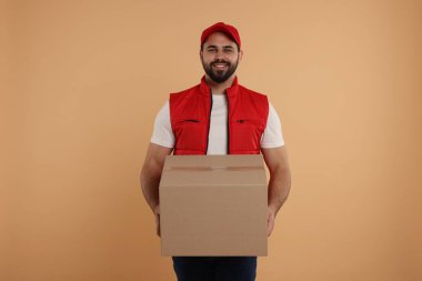 Açık kahverengi arka planı olan mutlu genç kurye.