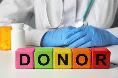 Sözcük donörü tahta küplerden yapılmış. Doktor beyaz masada oturuyor, yakın plan.