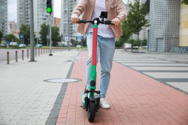 Şehir caddesinde modern elektrikli scooter kullanan adam, yakın plan.