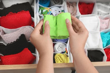 Kadın iç çamaşırları çekmecede, üst katta, organizatörlerin yanında çorap sarıyor.