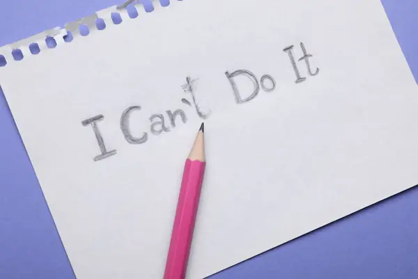 Motivation concept. Paper with changed phrase from I Can't Do It into I Can Do It by erasing letter T on violet background, top view