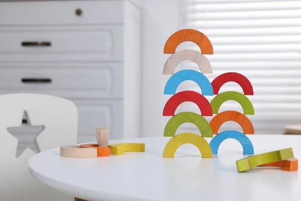 Colorful wooden pieces of educational toy on white table in room. Motor skills development