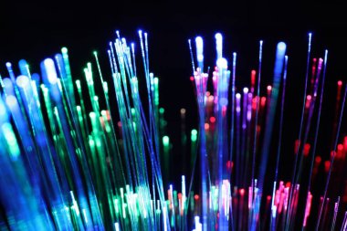 Optik fiber iplikler siyah arkaplanda farklı renk ışıkları iletiyor, yakın plan