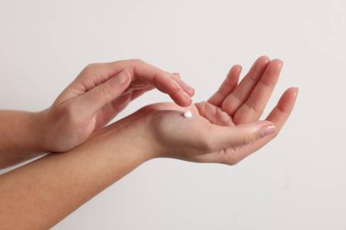 Beyaz arka planda kozmetik krem süren kadın, yakın plan.