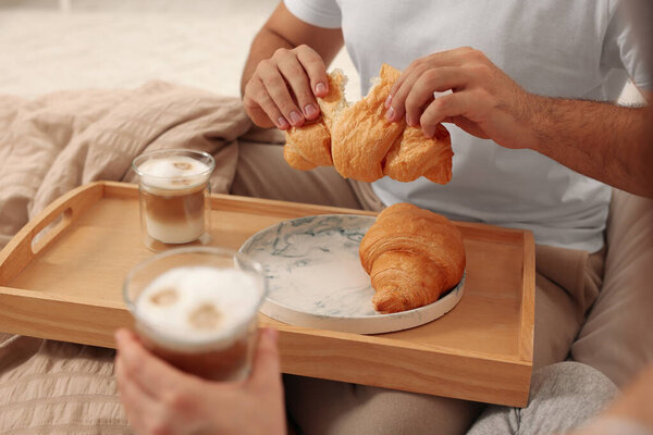 Couple having breakfast together on bed at home, closeup