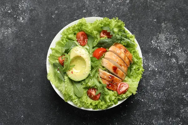 Delicious salad with chicken, cherry tomato and avocado on grey textured table, top view