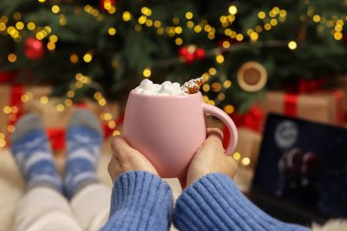 Lezzetli kakao içen ve evde Noel filmi izleyen bir kadın.