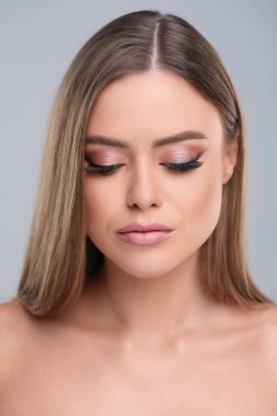 Gri arka planda makyajlı güzel bir kadın.