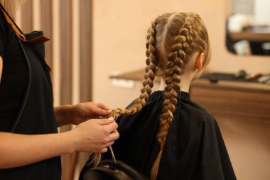 Profesyonel kuaför. Güzellik salonunda kız saçı örüyor. Yakın plan.