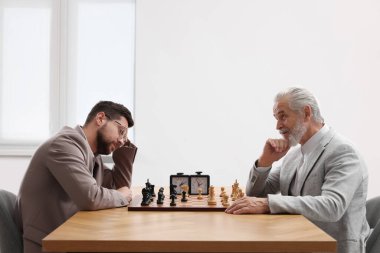 Erkekler turnuvada içeride satranç oynuyorlar.
