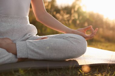 Dışarıdaki yoga minderinde Padmasana egzersizi yapan kadın, yakın plan. Lotus pozu