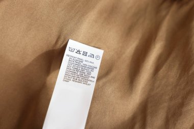 Bej rengi giysilerde farklı dillerde giyinme etiketi, yakın plan