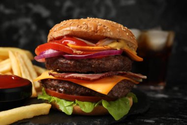 Köfteli lezzetli hamburger, pastırma, peynir, sebze ve marul siyah masada, yakın plan.
