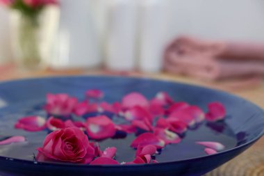 Masada suyla birlikte pembe gül ve taç yaprakları, yakın plan.