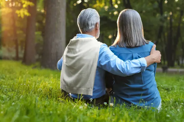Sevecen yaşlı çift parkta, arka planda ve mesajlaşmak için birlikte vakit geçiriyorlar. Romantik randevu