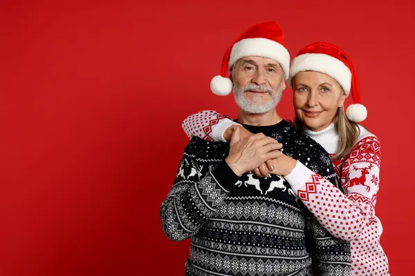 Couple Aîné Pulls Noël Chapeaux Père Noël Sur Fond Rouge — Photo
