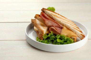 Jambonlu lezzetli sandviçler, marul ve erimiş peynirli beyaz ahşap masa, yakın plan. Metin için boşluk