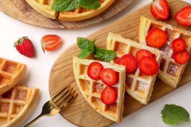 Beyaz masada çilekli, nane ve çatallı Belçika waffleları.