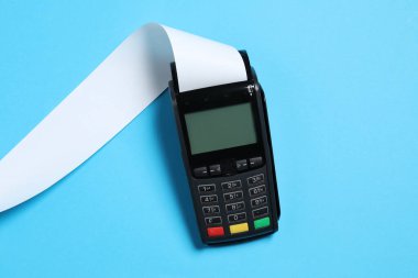 Açık mavi arkaplan üzerindeki makbuz için termal kağıtlı ödeme terminali, üst görünüm