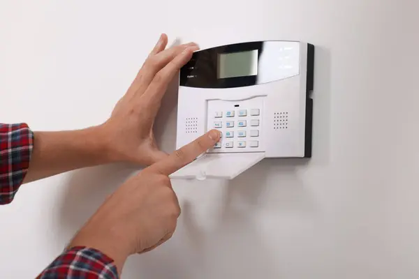 Man entering code on security alarm system at home, closeup