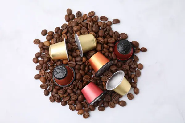 Many coffee capsules and beans on white background, top view