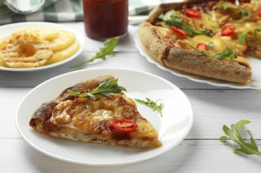 Beyaz ahşap masada lezzetli bir ananaslı pizza tabağı.