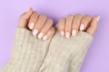 Tırnaklarında beyaz oje olan kadın menekşe arkaplan, üst görünüm