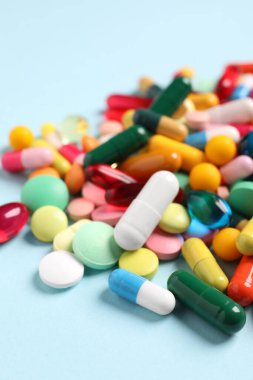 Açık mavi arka planda birçok farklı hap, yakın plan