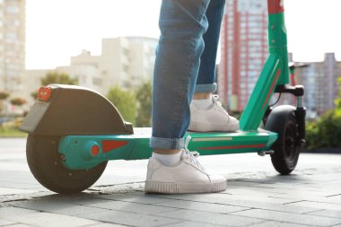 Şehir caddesinde modern elektrikli scooter kullanan kadın, yakın plan.