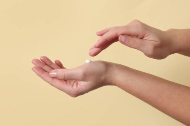 Bej arka planda kozmetik krem süren kadın, yakın plan.